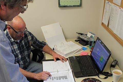 Two HECO technicians reviewing charts and specifications on a computer.