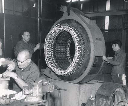 Vintage image of HECO technicians handling an electric motor's stator.