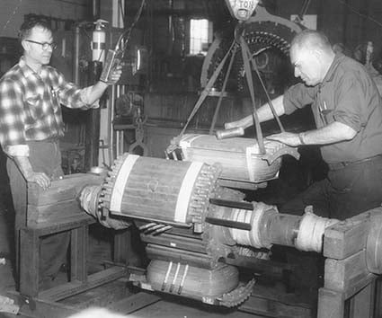 Vintage photo of HECO technicians handling an electric motor's rotor.