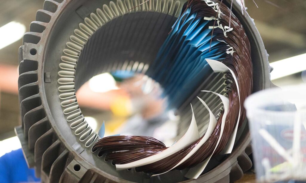 An electric motor in the midst of a repair, with half of its wiring missing.