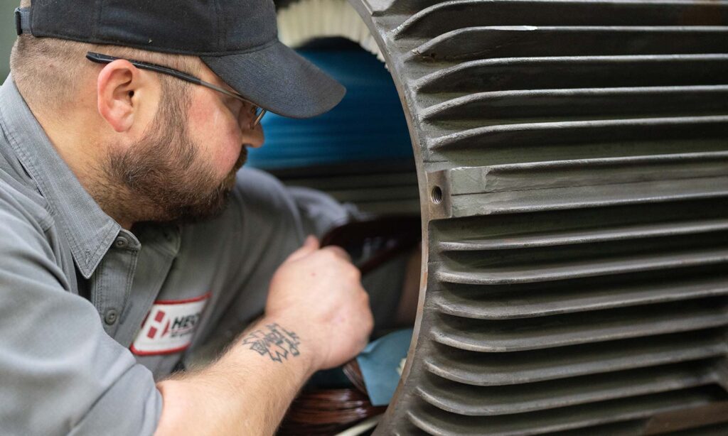 HECO technician reaching their arm through an electric motor going through a repair.