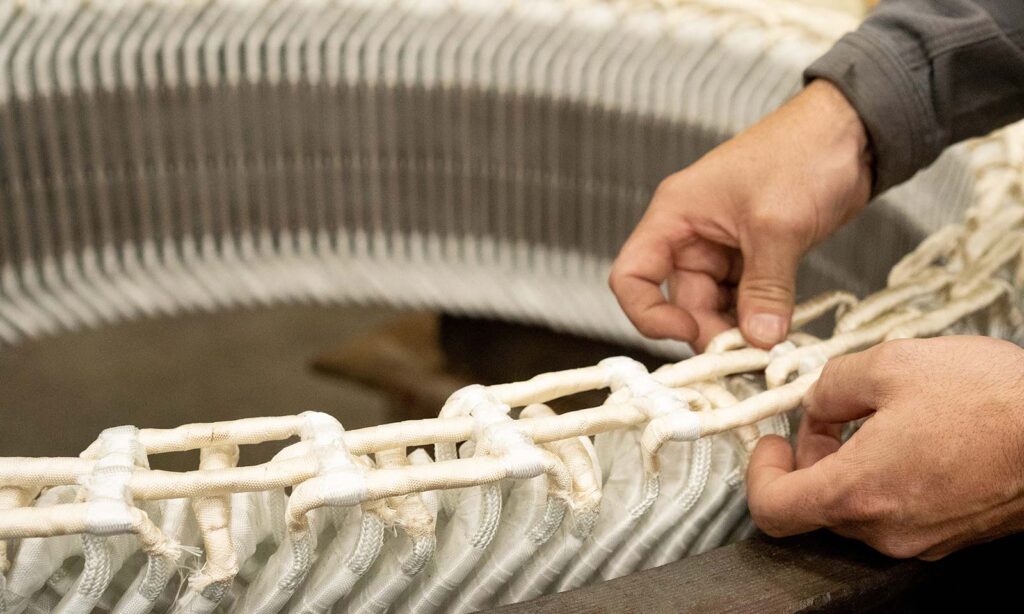 Expert hands wrapping coils with insulating tape for electrical protection.