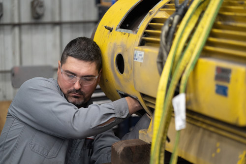 Employee Reaching In Motor To Repair